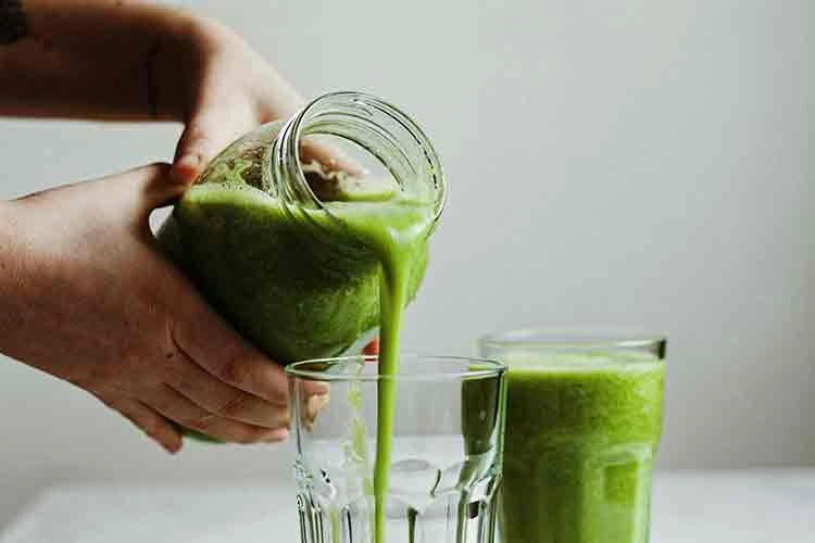 Green smoothie being poured into a glass