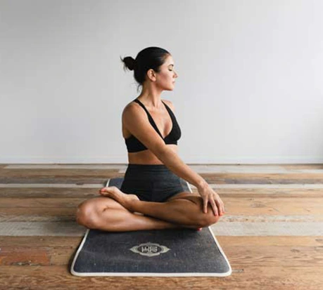 Woman sitting on a yoga mat cross-legged stretching