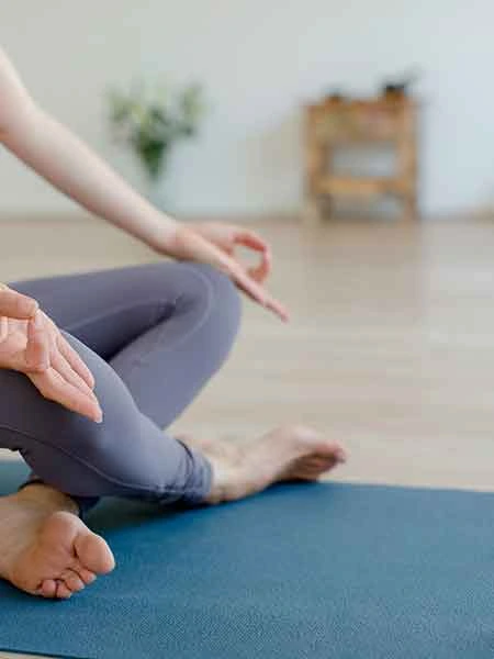 women sitting on a yoga mat doinf a meditation pose